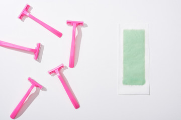 top view of female pink razors and depilation stripe on white background