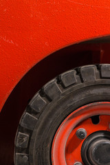 Red dirty forklift wheel in a factory with dirty tyres and dirty nuts and bolts. Vivid bright colours and dirty tyres. Covered in dust and grime