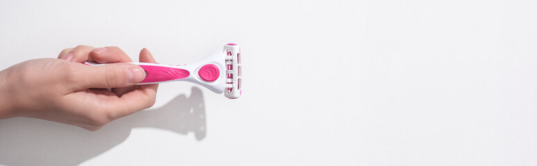 cropped view of woman holding female pink razor on white background, panoramic shot