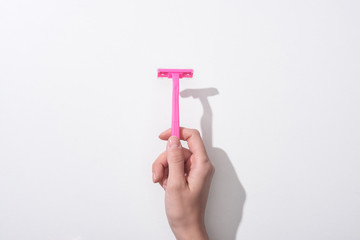 cropped view of woman holding female pink razor on white background