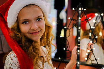Merry Christmas and happy holidays. A cute blonde girl in a Santa Claus hat stands next to a...