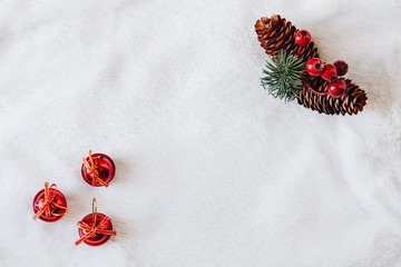 top view of Christmas composition on white snowy background for greeting card. pine cones and little christmas red balls
