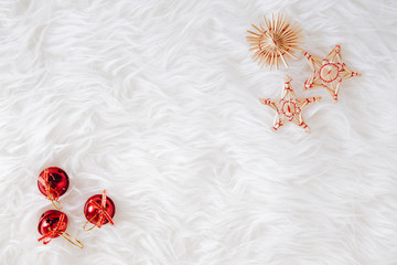 top view of Christmas composition on white snowy background for greeting card. straw decoration and little christmas red balls