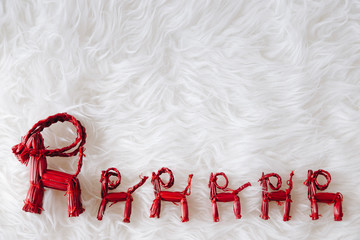 top view of Christmas composition on white snowy background for greeting card. Row of red straw reindeers with little straw stars