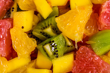 Background of the chopped exotic fruits. Mango, oranges, grapefruit and kiwi
