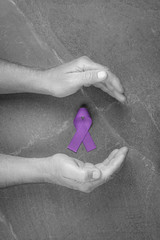 Hands holding purple ribbons top view