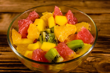 Salad with mango, oranges, grapefruit and kiwi fruits in a glass bowl on wooden table
