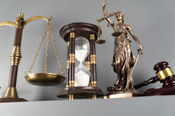 Judge and justice concept. Themis statue, scale and hourglass on off-white background.