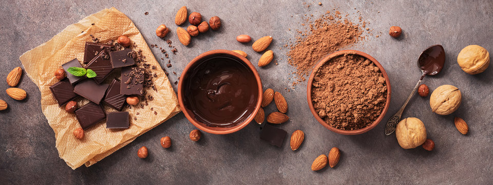 Border with chocolate, nuts and cocoa powder on a dark background. Overhead, flat lay
