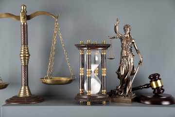 Judge and justice concept. Themis statue, scale and hourglass on off-white background.