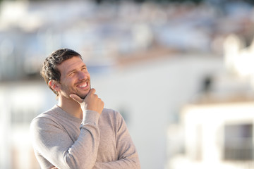 Happy pensive adult man looking at side in a town