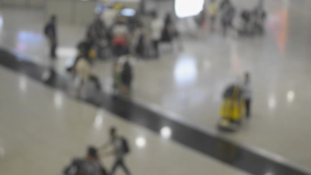 People customers walking with luggage at international airport in asian city. Blurred view of passengers with buggage in hands is having time in terminal room, waiting for arrival or departure