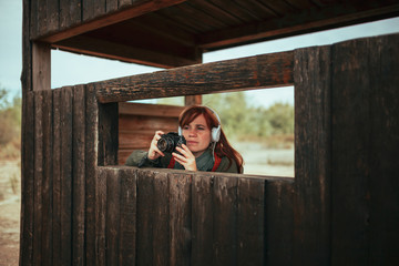 Young woman taking photos from wooden hut in the forest