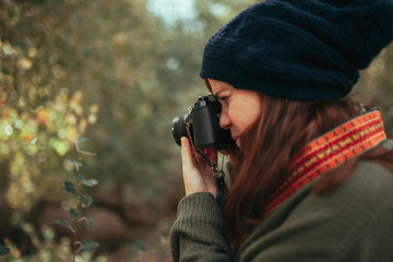 Young woman taking photos in the forest with an old camera