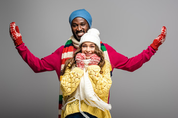 happy interracial couple in winter outfit on grey background