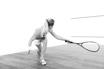 Attractive sports girl holding racket and playing squash on a court