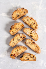 Tasty traditional Italian homemade biscotti or cantuccini cookies with hazelnuts, almonds and walnuts on a light gray background. Top view, flat lay