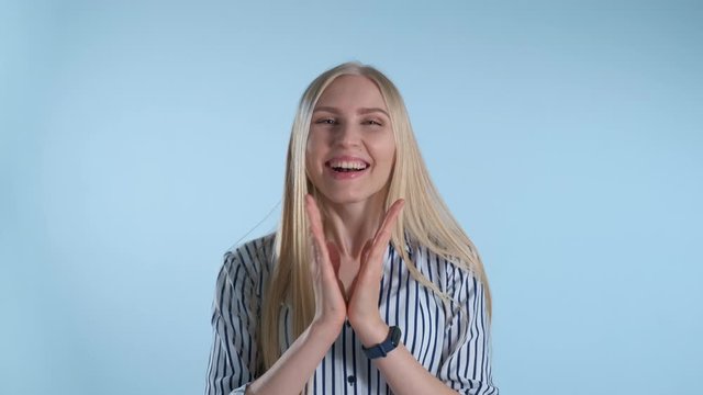 Woman clapping her hands, waiting for something interesting. Blue background.