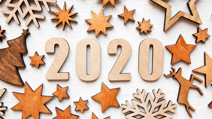 The beautiful christmas background with a lot of small wooden decorations and wooden numbers 2020 on the white wooden desk.