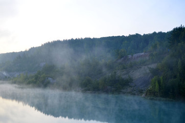 Morning mood with sunrise with a haze over a lake in the mountains. That artificial lake formed after the extraction of chalk in an industrial quarry at Krasnoselsky village in the Belarus.