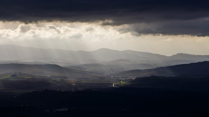 Fototapeta premium Italian landscape in the hills and mountains under cloudy sky illuminated with sunrays