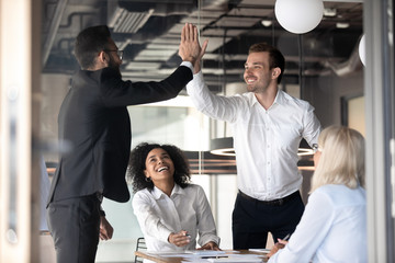 Excited male colleagues give high five celebrating shared success