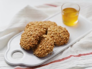 oatmeal cookies, honey and nuts on a white towel. Rustic style. White background. High key in food pictures