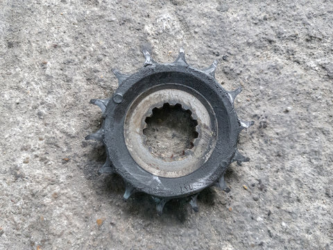 Old dirty sprocket gear motorcycle lying on the cement floor after used for long time, maintenance and repair concept.