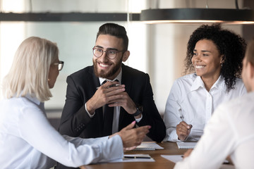 Smiling diverse colleagues discussing ideas at office briefing