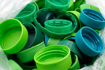 Green plastic bottle caps sorted by colors in transparent single use plastic bags. PP an PET...