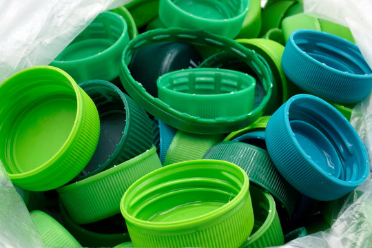 Green plastic bottle caps sorted by colors in transparent single use plastic bags. PP an PET pollution.