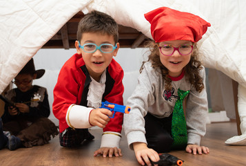 Children dressed in colored glasses playing in a makeshift hut.