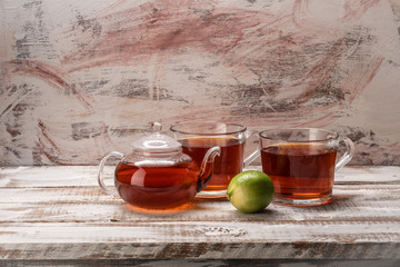 Still life food on a bright table of boards glass teapot and mugs with tea and lemon on a colorful background