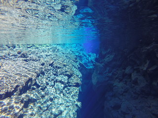 Unterwasser Aufnahme mit Felsen, Spalten und tief blauen, klaren Wasser