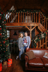 Obraz na płótnie Canvas pregnant wife with husband posing next to a Christmas tree