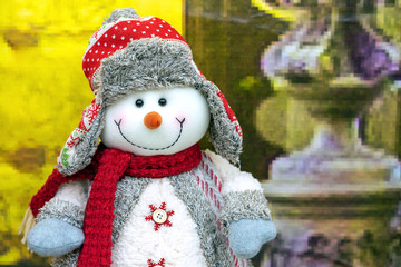 Cristmas soft toy of a snowman in a sweater, red scarf and hat.