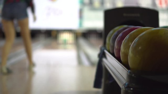 Bowling balls close-up on the background of a bowler girl throwing a ball on skittles. Recreation and entertainment at the bowling club