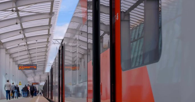 Passengers got out the train and walk along the platform of the ground metro station, train doors are closing