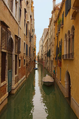 Obraz na płótnie Canvas Long and narrow canal with emerald water between medieval buildings. Boats moored near walls. Picturesque landscape of Venice. Famous touristic place and travel destination in Europe. Venice, Italy