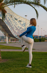 Fitness sport girl in sportswear doing fitness exercise in the street,outdoor sports. Sports girl in light clothing is engaged in gymnastics, fitness woman is stretched