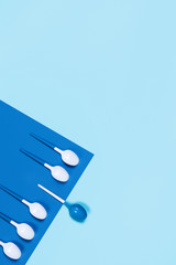 Picture of white and blue plastic spoons on blue background.