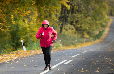 Middle age woman wearing sportswear and running in forest.