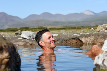 Man bathing and relaxing in hot springs during summer day. Natural hot geothermal springs and pool in the Iceland, Europe.