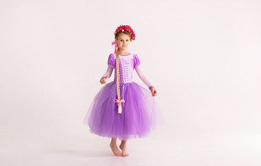 Little blonde girl wearing purple fairy princess dress on white background. Kids costume for new...