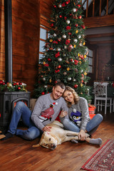 Obraz premium family on the floor against the background of a Christmas tree with a dog