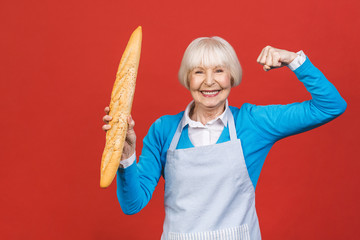 Taste of France. Portrait of a joyful senior woman holding a fresh delicious baguette bread smiling...