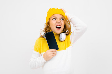 European cute girl with big headphones and smartphone listens to music and grimaces over white background