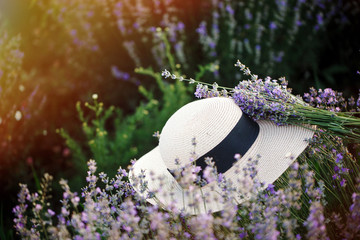 A woman's hat lies on lavender flowers in the purple field.