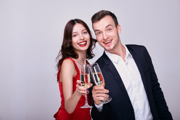 Smiling couple with glasses of champagne on the background.
