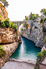 View on Fiordo di Furore arc bridge built between high rocky cliffs above the Tyrrhenian sea bay in Campania region. Unique cove under the cliffs, natural gorge, canyon or fiord - obrazy, fototapety, plakaty